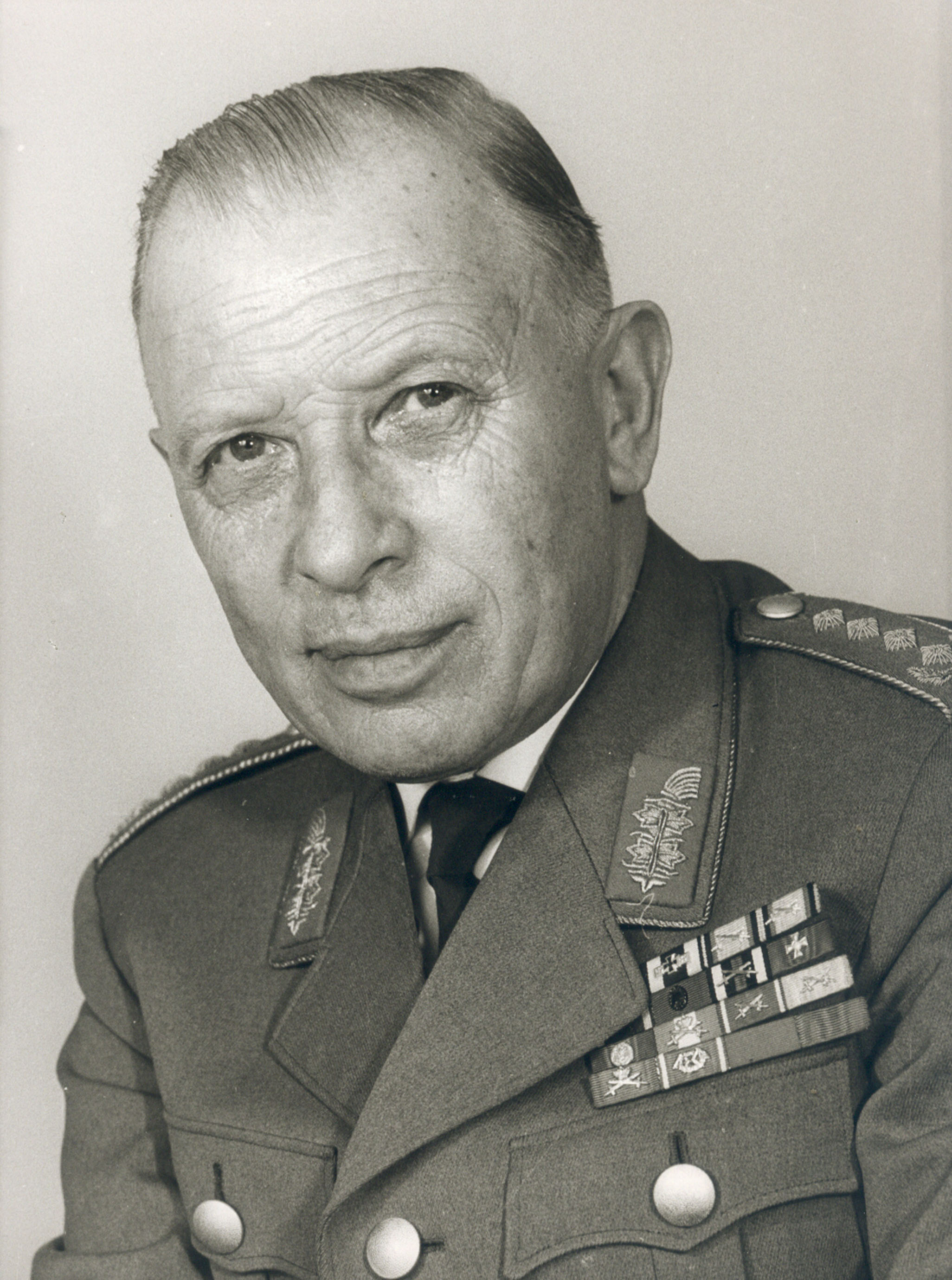 Portraitfoto von Heusinger in Uniform, der ernst in die Kamera schaut.