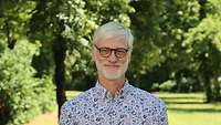 Dr. Christopher Oestereich steht auf einer Wiese im Garten des ZMSBw