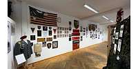 Ausstellungsraum mit Wappen, Bildern und Fahnen an der Wand.