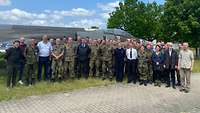 Eine 40-köpfige Besuchsgruppe lässt sich vor einem Kampfflugzeug fotografieren.