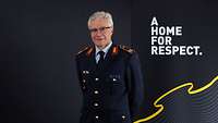 Brigadegeneral Alfred Marstaller vor einer Werbewand mit dem Invictus Slogan "A Home for Respect"