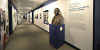 Ein langer Gang mit Infotafeln und der Büste eines Mannes