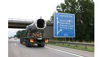 Ein Flugzeugteil liegt auf einem LKW und wird auf der Straße transportiert. 