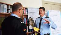 Colonel Hartmann with a yellow book (Handbuch IF 1957) in his hand talking to a lieutenant colonel