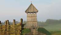 Frontansicht einer Turmhügelburg aus Holz auf einem begrünten Hügel