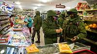 Soldaten ohne Hoheitsabzeichen stehen zwischen Zivilisten in einem Lebensmittelladen auf der Krim.
