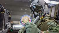 Ein Pilot hält seinen Patch für die Mission Counter Daesh in die Kamera