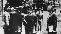 Hitler reicht einem Mann die Hand zur Begrüßung, daneben stehen Claus Schenk Graf von Stauffenberg, Wilhelm Keitel.