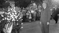 General Kielmannsegg arrangiert einen Kranz zum Gedenken an die Opfer des 20. Juli 1944, Adenauer steht davor.