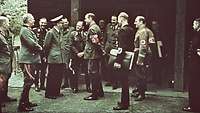 Hitler steht umgeben von Generalen und Parteifunktionären in der Wolfsschanze.
