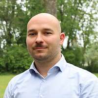 Mann mittleren Alters lächelt freundlich in die Kamera