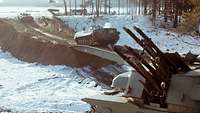 Schützenpanzer der NVA fahren während einer Übung durch schneebedecktes Gelände.