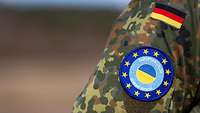 Blaues Wappen mit gelben Sternen (EU) auf einer Felcktarn Uniform