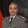 Oberst in Uniform vor Truppenfahne