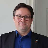 Mann in Hemd und Sakko vor Glaswand mit ZMSBw Wappen