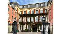 Zweiflügeliges Backsteingebäude mit Innenhof, Fassade mit Efeu überwuchert