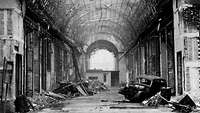 Zestörte Eimkaufspassage, Berlin 1945, trümmer und ein Autowrack, helles Licht im Bogen am Ende