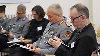 Männer in zivil und Uniform erfassen die neusten Informationen auf einem Block
