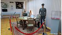 runder Tisch mit vier Stühlen auf einem eckigen Teppich mit zwei Puppen in Uniform