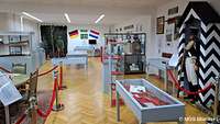 Ausstellungsraum mit Vitrinen und vielen Bildern an der Wand