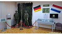 Ausstellungsraum mit Vitrinen, Bildern und Flaggen von Deutschland und der Niederlande an der Wand