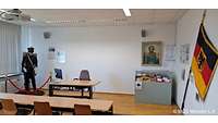 Hörsaal mit Tischen und Stühlen und eine Figur mit Uniform