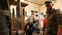 Ein Soldat betrachtet eine alte Gasmaske und Munitionsreste in einer Ausstellung in einem Bunker