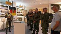 Ein Offizier erklärt einen bebilderten Ausstellungsabschnitt zu Bundeswehreinsätzen auf dem Balkan. 