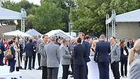 Verschiede Menschen in Uniform und Zivilkleidung im Gespräch.