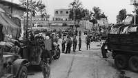 Israelische Soldaten stehen in der Mitte einer Straße, davor und dahinter militärische Fahrzeuge