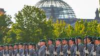 Soldaten des Wachbataillons in Heeresuniform vor Bäumen und Reichstag