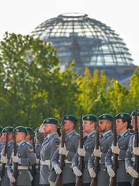 Soldaten des Wachbataillons in Heeresuniform vor Bäumen und Reichstag