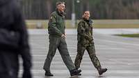 Ein Soldat und eine Soldatin gehen nebeneinander über einen Platz und sprechen miteinander.