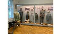 Eine Vitrine mit verschiedenen Waffen, Helmen und Bildern