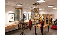 Schellenbaum in der Mitte eines Ausstellungsraumes mit mehreren Vitrinen