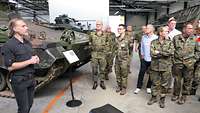 Ein Mann spricht vor einem Schützenpanzer stehend zu einer Gruppe von Museumsgästen
