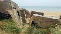 Betonbrocken eines zerstörten Bunkers an einem Strand in Frankreich.