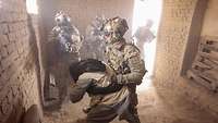 Soldaten des KSK in einer Häuserruine, ein Soldat nimmt eine zivile Person in Gewahrsam