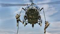 Zwei Soldaten seilen sich aus einem Hubschrauber ab.