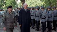 Foto: Ein Mann in Uniform, ein Mann im Anzug laufen an Formation Soldaten entlang