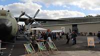 großes grünes Militärflugzeug, interessierte Menschen auf Ausstellungsfläche