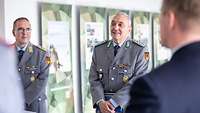 Ein Mann in Uniform spricht zu einer Menschengruppe.